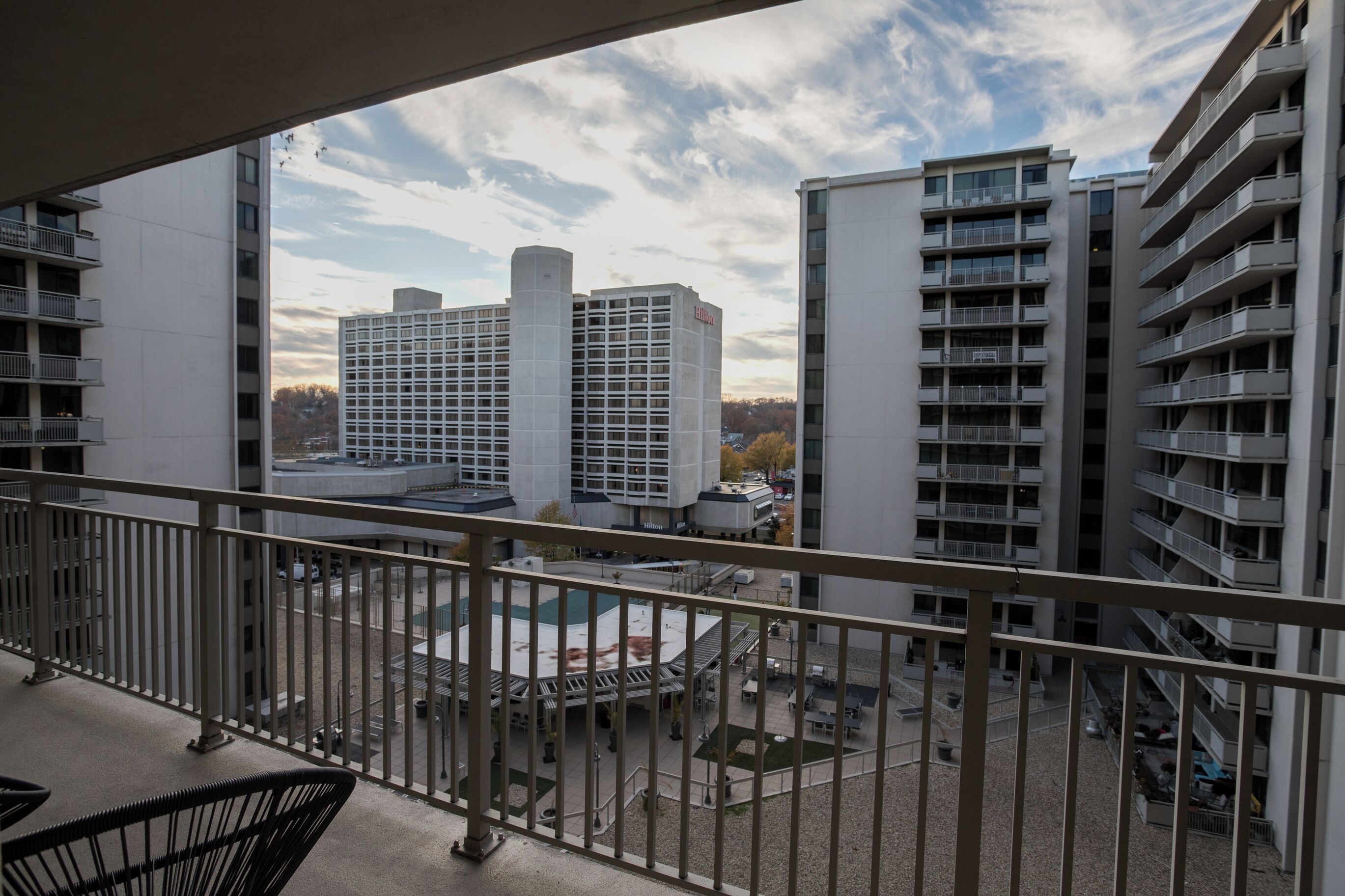 A view from a balcony overlooking a courtyard with a pool, surrounded by modern buildings.