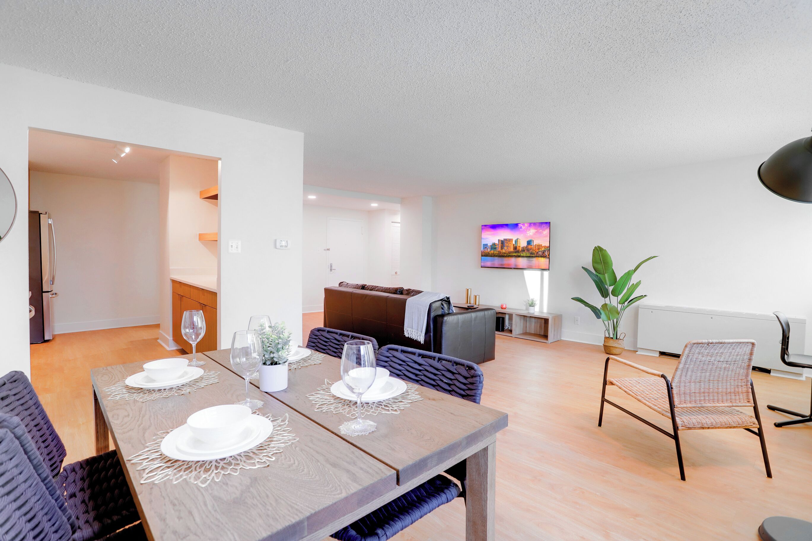 A modern living room with a dining area, a sofa, a TV, and a potted plant.