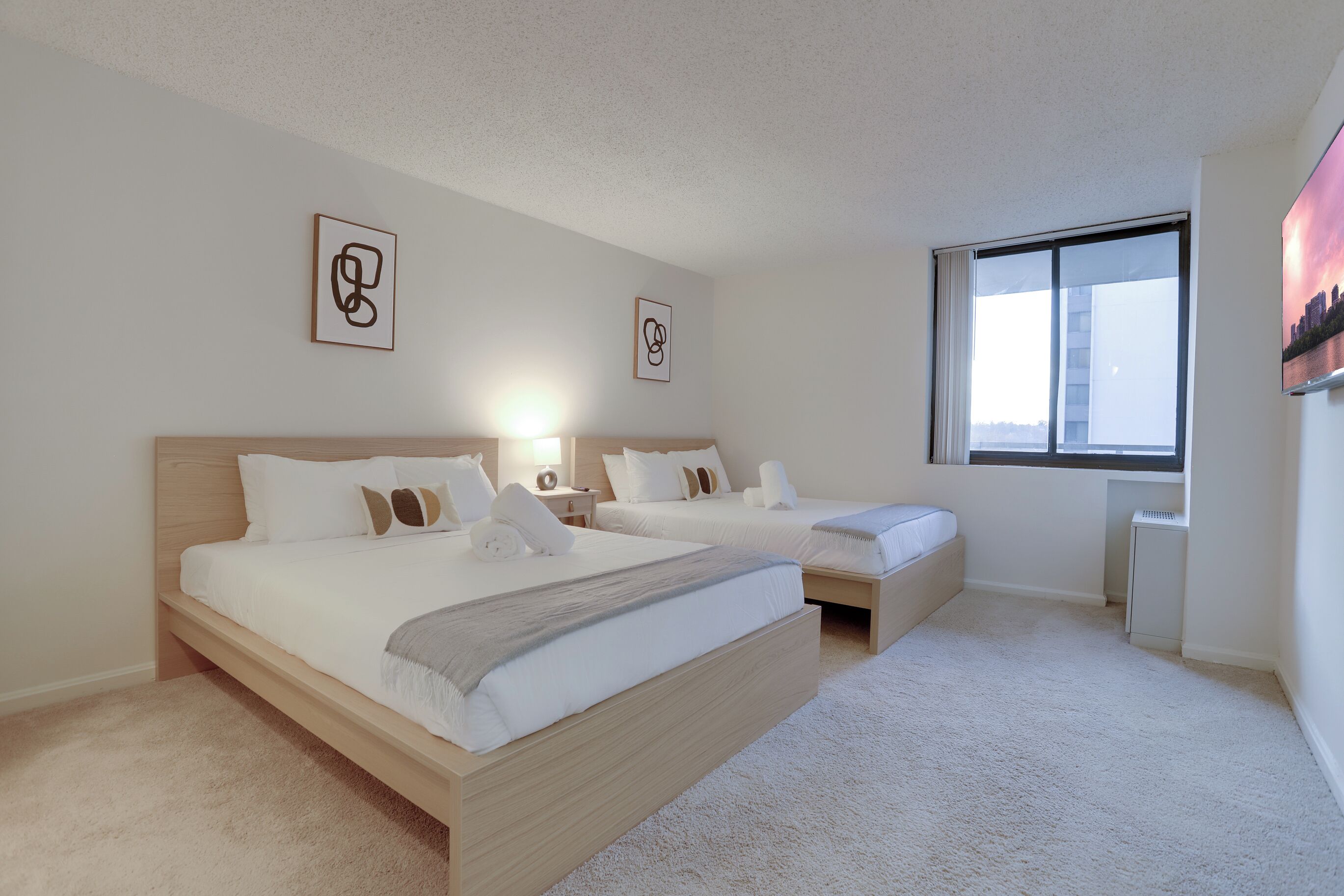 Une chambre d’hôtel moderne avec un grand lit, des tables de chevet et une fenêtre donnant sur la ville.