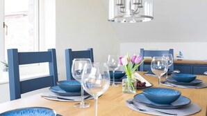 A dining table set with blue plates, glasses, and a vase with flowers. - Cottage with 3 ensuite bedrooms and Sea Views.  North Devon Heritage Coast. (Bideford)