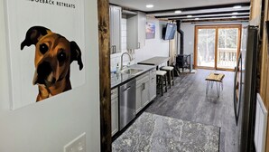 A modern kitchen with stainless steel appliances, a wooden floor, and a large window overlooking a deck. - Shamrock 73 - 2br/2ba - Pet Friendly - Fully Renovated! (Snowshoe)