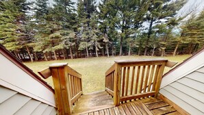 A wooden deck leading to a grassy area with tall trees in the background. - Shamrock 73 - 2br/2ba - Pet Friendly - Fully Renovated! (Snowshoe)