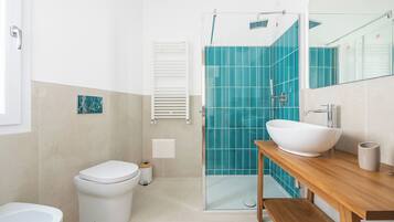 A modern bathroom with a glass shower enclosure, a white sink, and a toilet.