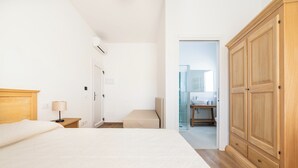 Un dormitorio con cama, mesita de noche, lámpara y armario.