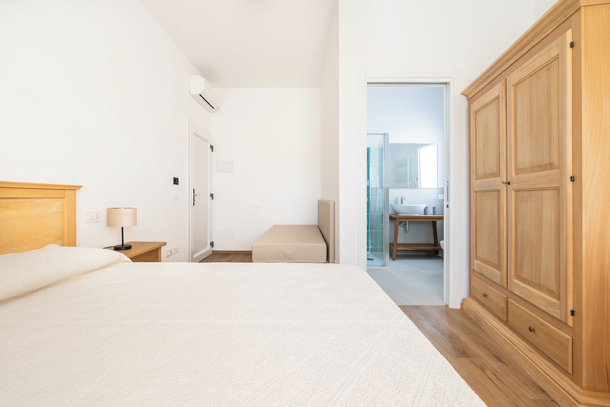 Un dormitorio con cama, mesita de noche, lámpara y armario.
