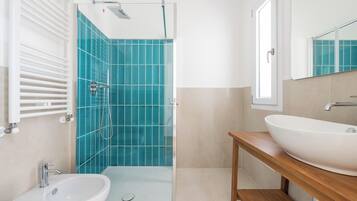Une salle de bain moderne avec une douche à parois de verre, un lavabo et un miroir.