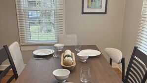 A dining room with a wooden table set for four, surrounded by chairs. - Charming 1925 Home In Broad Ripple - Sleeps 6, Modern Comforts & Prime Location (Indianapolis)