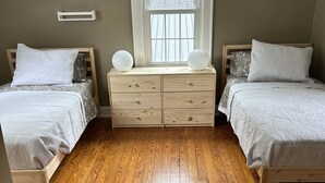 A bedroom with two beds, a dresser, a window, and wooden flooring. - Charming 1925 Home In Broad Ripple - Sleeps 6, Modern Comforts & Prime Location (Indianapolis)