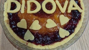 Une tarte portant le nom « DIDOVA » et décorée de motifs en forme de cœur, posée sur une table en bois.