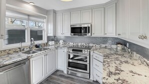 Una cocina moderna con armarios blancos, electrodomésticos de acero inoxidable y encimera de granito.