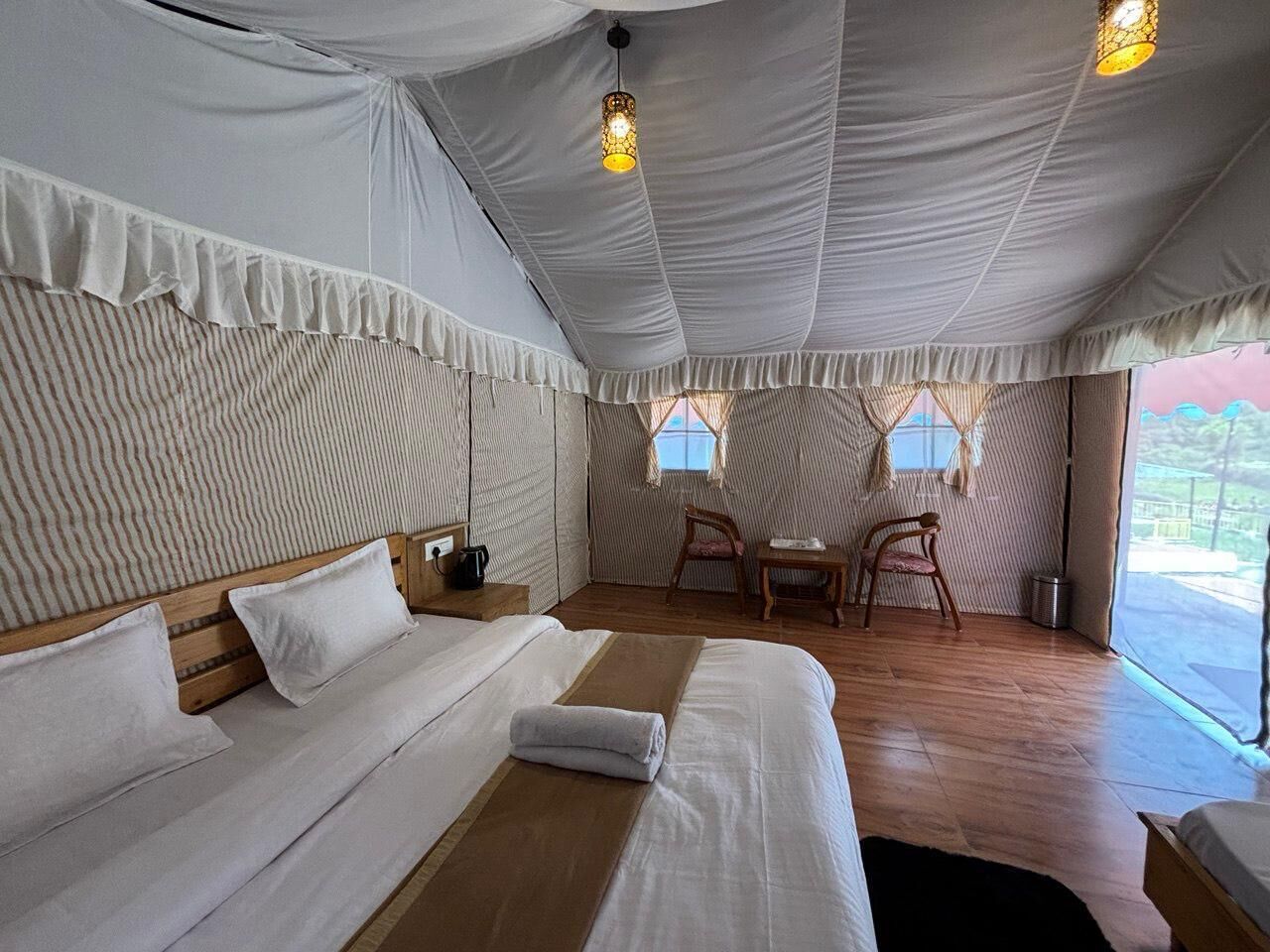 A tent-style room with a bed, a small table, and chairs.