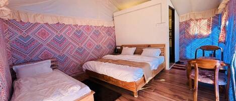 A cozy tent-style room with two wooden beds, a small table, and a chair.