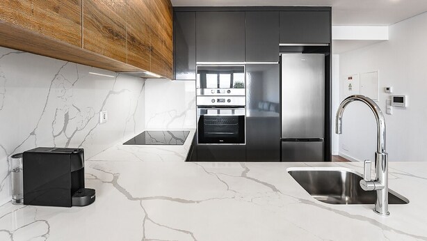 Eine moderne Küche mit Einbauofen, einem Edelstahlkühlschrank und einem eleganten Wasserhahn.