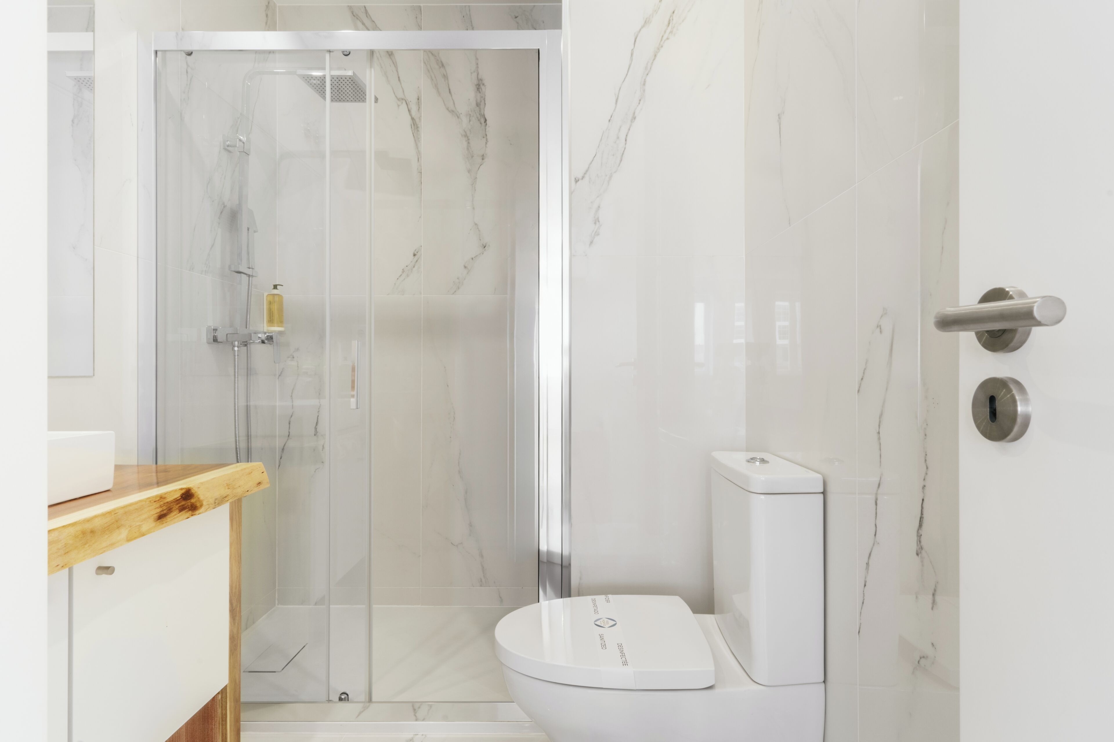 A modern bathroom with a glass-enclosed shower, a white toilet, and a wooden countertop.