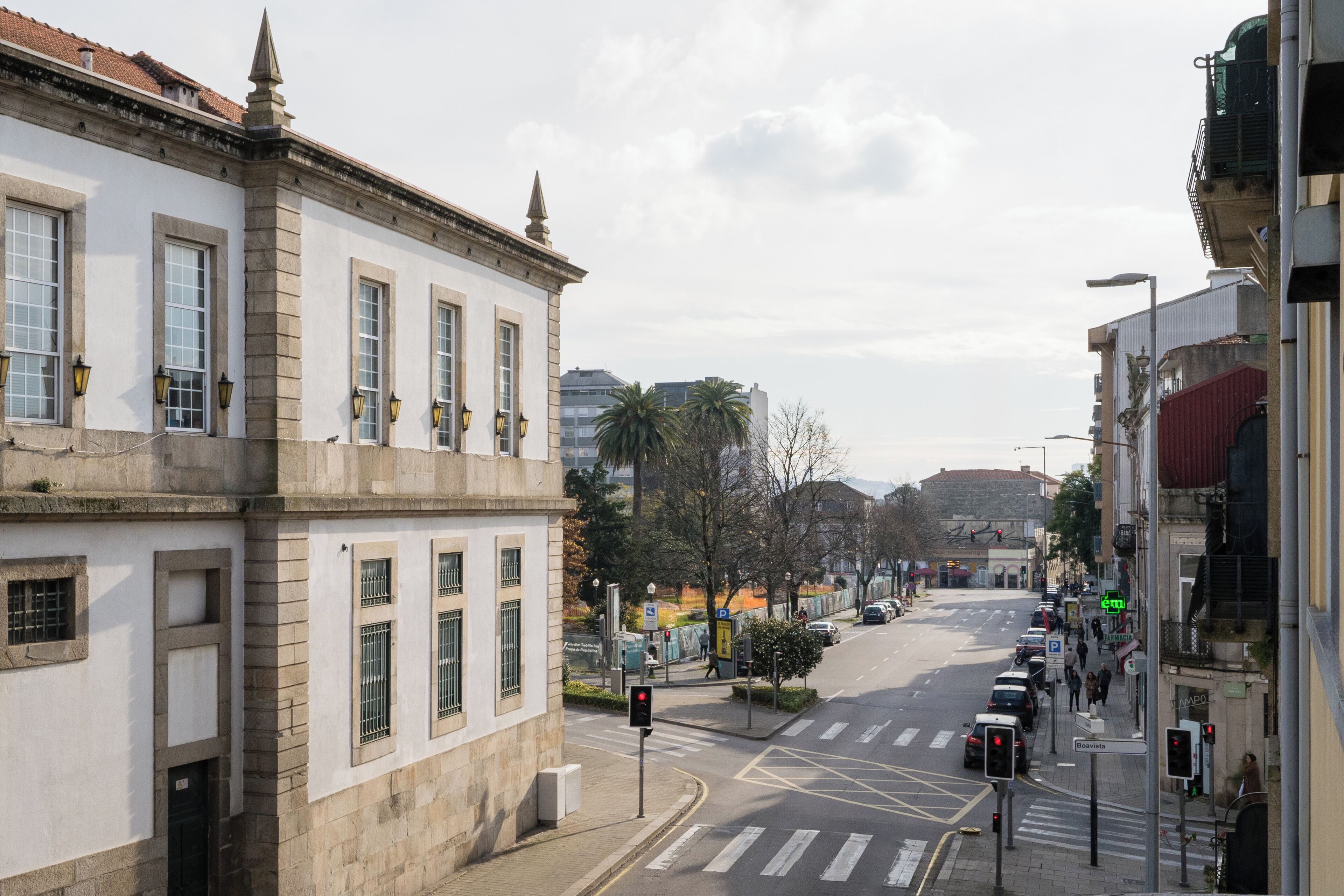 Vista de una calle con un edificio que destaca por sus grandes ventanales y una entrada en esquina.