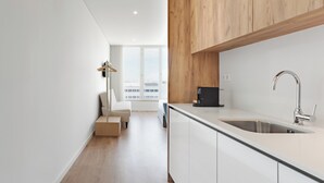 Eine moderne Küche mit einem großen Spülbecken, Holzschränken und Blick auf die Stadt durch große Fenster.