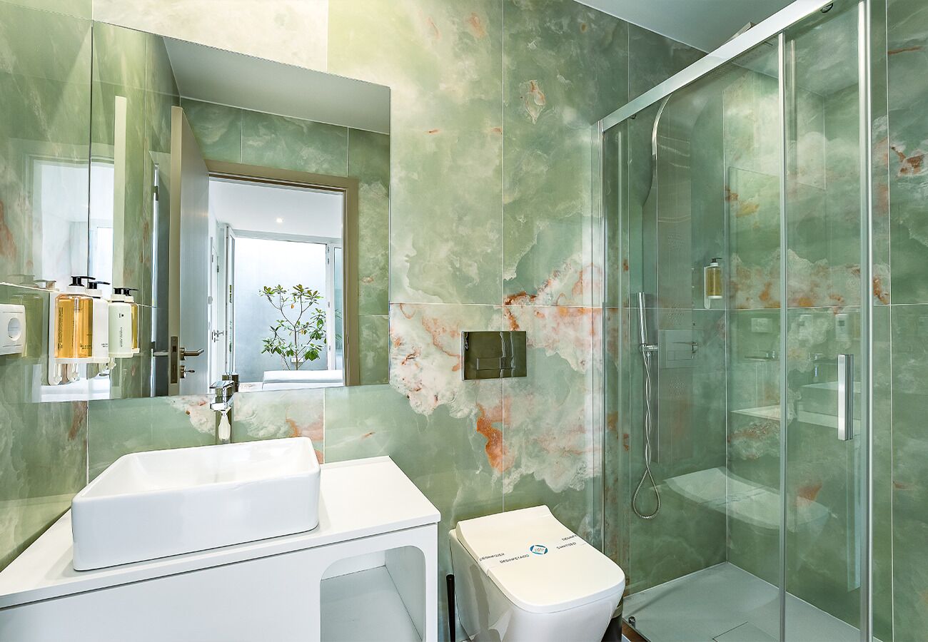 Une salle de bain avec une douche à parois de verre, un lavabo blanc et des toilettes.