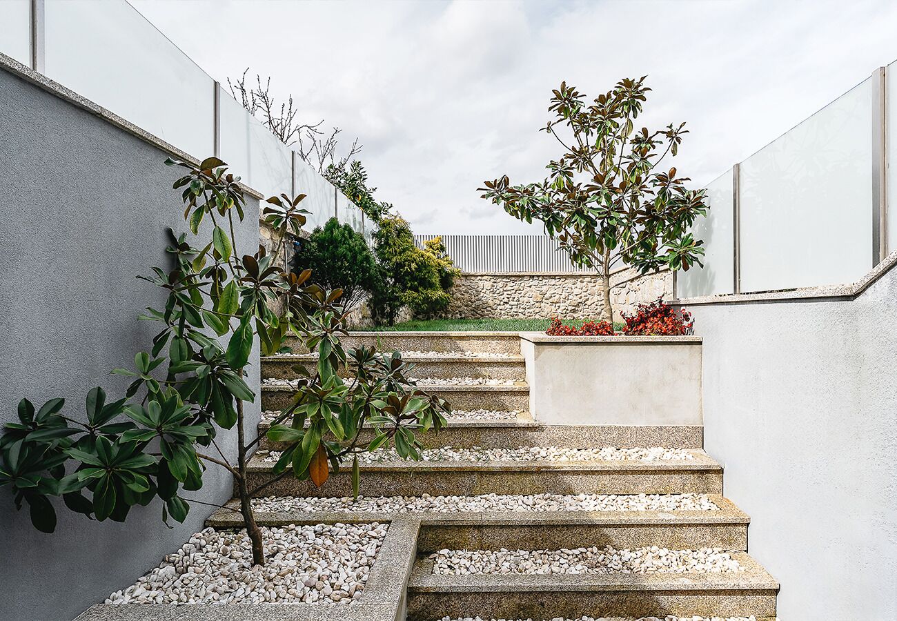 Un escalier aux marches blanches et un jardinier orné de fleurs rouges.