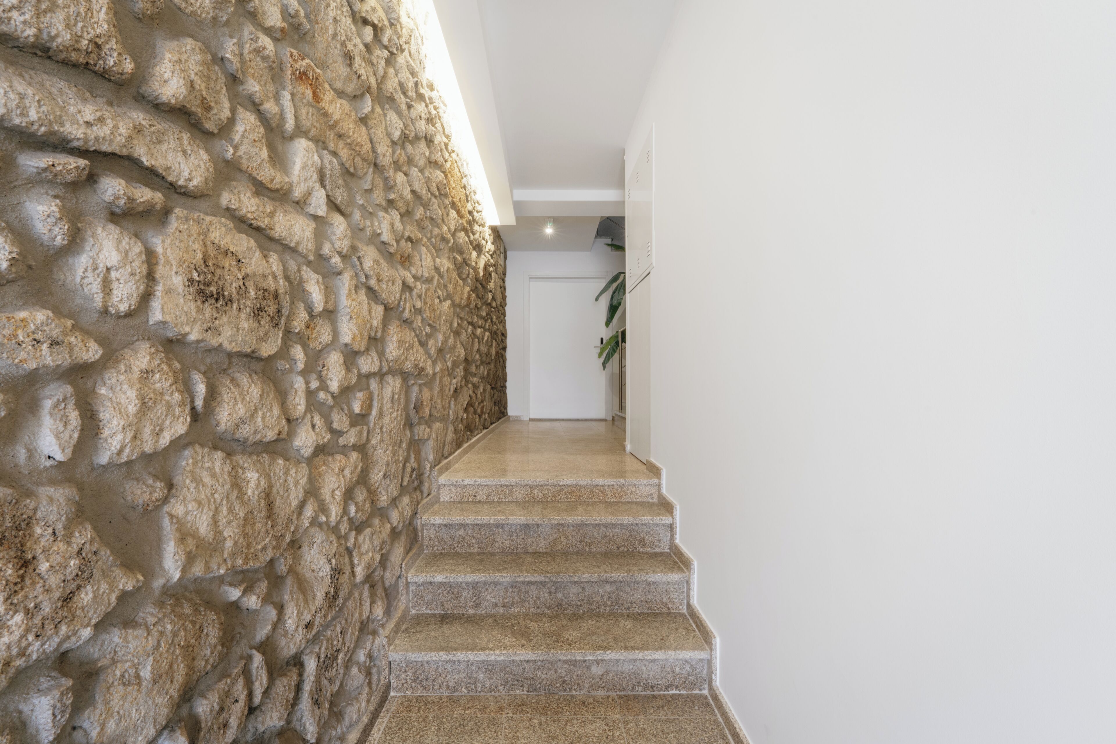 A staircase with stone walls and a white door at the top.