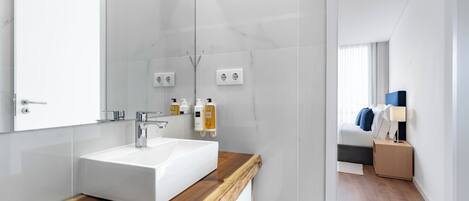 A modern bathroom with a white sink, wooden countertop, and a large mirror.