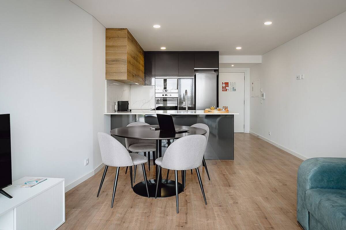 Una cucina moderna con zona pranzo, televisore e divano blu.