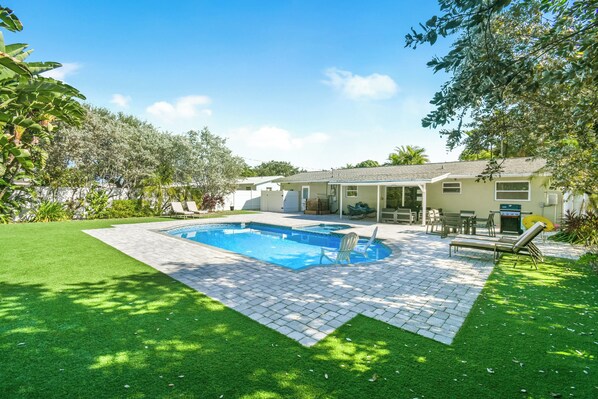 Une propriété résidentielle dotée d’une piscine, d’un patio et d’une pelouse.