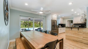 A modern kitchen with a wooden dining table, built-in appliances, and a view to the outdoors. - Charming 4-Bedroom Beach Bungalow with Idyllic Pool & Backyard (Tequesta)