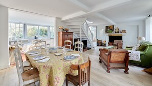 A spacious living room with a dining area, a staircase, and a green sofa.