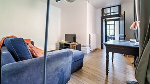Una sala de estar moderna con un sofá, una mesa de madera, una televisión y un ventanal grande.