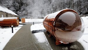 Een besneeuwde buitenruimte met grote cilindervormige constructies, mogelijk voor opslag of presentatie, en een verhard pad dat door het beeld loopt.