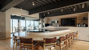A modern kitchen with a central island, bar stools, and a large window offering a city view.