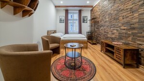 A cozy room with a bed, two chairs, a small table, and a wooden wall.