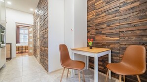 A modern dining area with a wooden accent wall, a white table, and two brown chairs.
