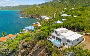 Une propriété située sur la côte, comprenant plusieurs bâtiments, une piscine et offrant une vue sur la mer.