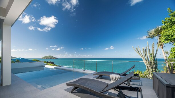 A poolside area with lounge chairs and a view of the ocean. - Beautiful SeaCrown Estate-Oceanfront- 6BR 5.5BA with Pool (St Thomas)