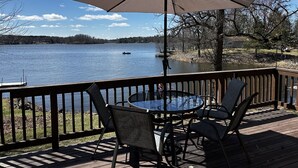 A deck with a table and chairs, overlooking a lake with a boat and dock. - Charming 2-bedroom house with WiFi, AC on Knife Lake in Mora Minnesota.  (Mora)