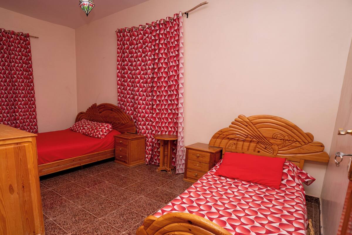 A bedroom with two wooden beds, a wooden dresser, and a small wooden nightstand.