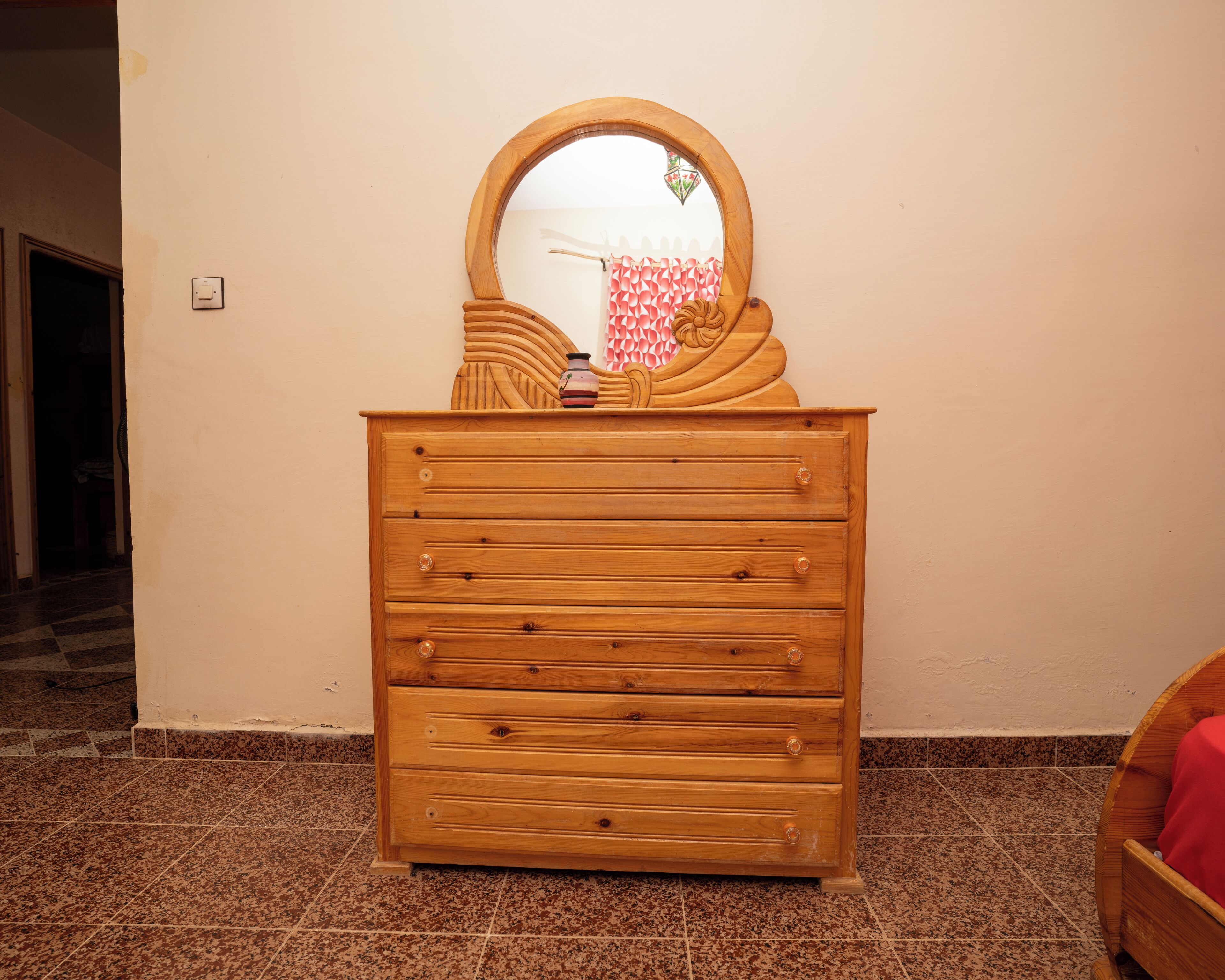 A wooden dresser with a mirror and a vase.