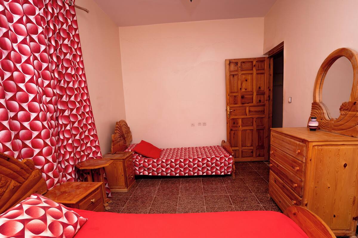 A bedroom with a bed, wooden dresser, and a door.