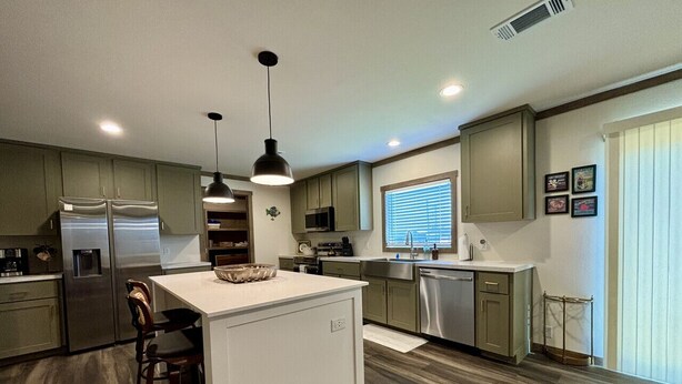 A modern kitchen with a central island, built-in appliances, and pendant lighting.