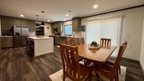 A compact kitchen with a central island, wooden dining table, and chairs.