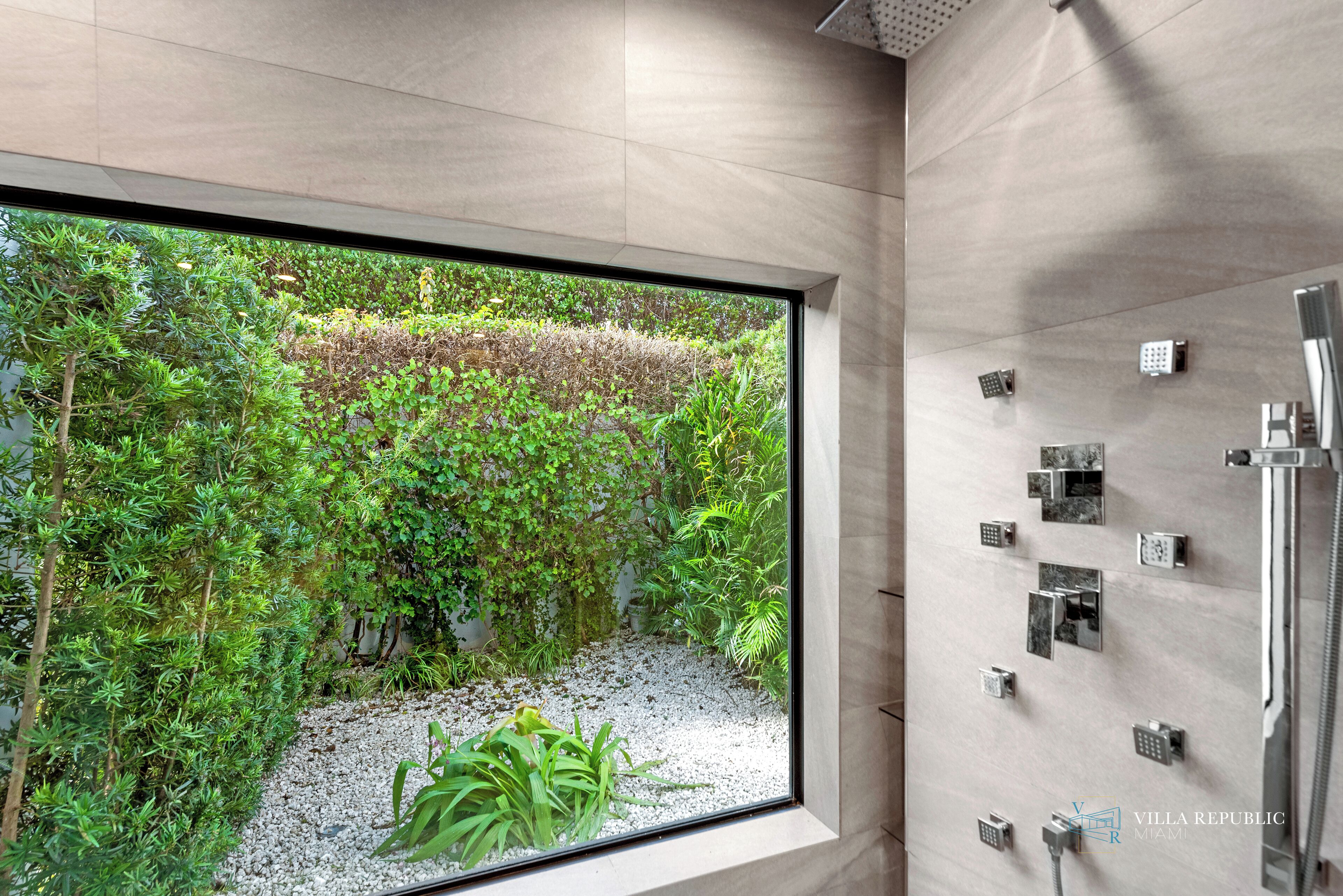 Un baño moderno con un ventanal grande, zona de ducha y panel de control en la pared.
