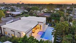 A modern house with a swimming pool, large windows, and a view of the city at sunset. - Villa Maya: A Luxury Retreat in North Miami Beach (North Miami Beach)