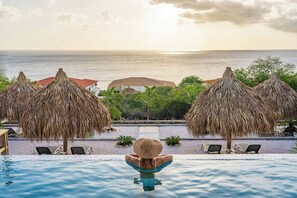 A poolside view with a person relaxing, overlooking a beach and ocean. - Your Private Beach Resort: LUXURY VILLA CASA CAS ABAO (Cas Abao)