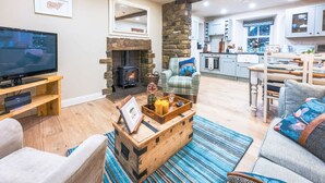 A cozy living room with a fireplace, a television, and a rustic coffee table. - River Dance Cottage (Leyburn)