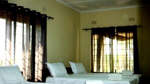 Une chambre d’hôtel avec deux lits simples, une fenêtre avec des rideaux et un mur uni.