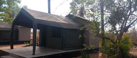 A tented accommodation with a flat roof and a small platform.
