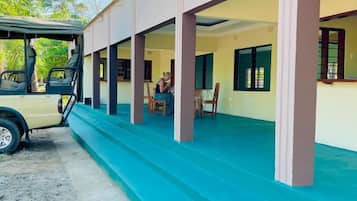 Guests can enjoy the building's open structure, supported by columns, amidst lush surroundings with palm trees.