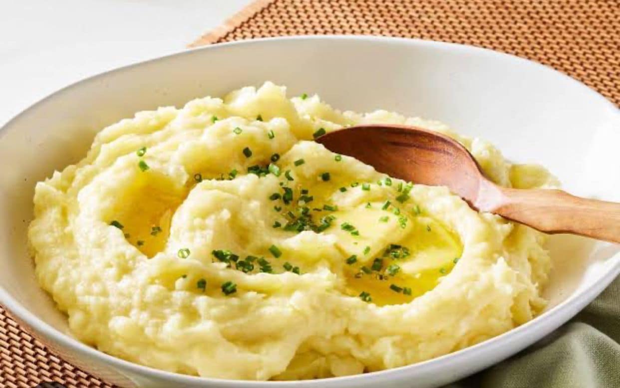 Un bol de purée de pommes de terre garnie de ciboulette et de beurre.