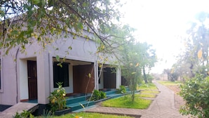 A building with a covered porch, a brick wall, and a paved pathway. - Royal South Luangwa Safaris Lodge (South Luangwa National Park)